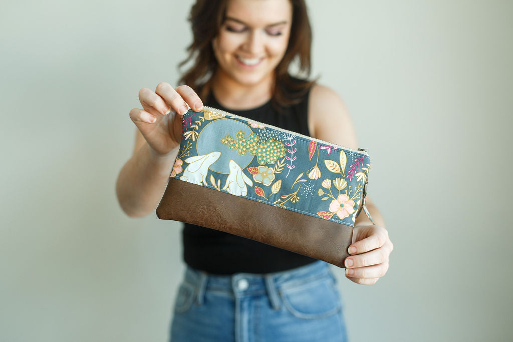 blue floral wristlet with bunnies and matching wrist strap and brown vinyl along bottom
